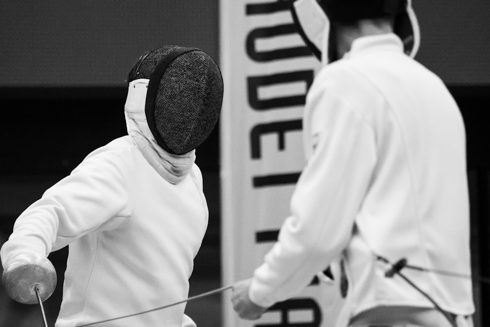 two men in fencing gear holding a rope