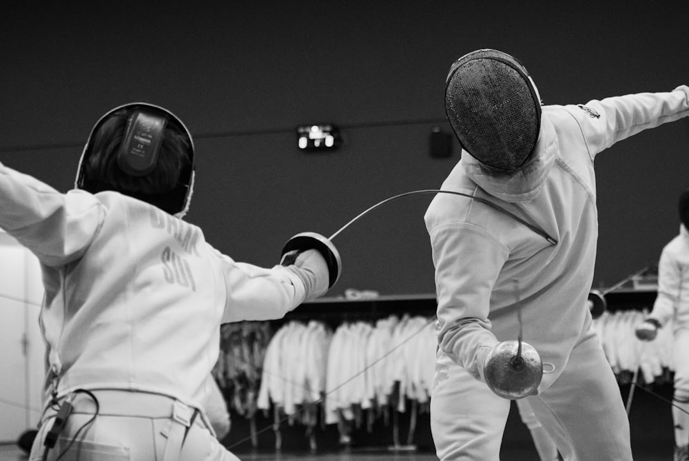 a couple of people that are standing up with fencing equipment