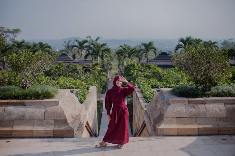 a woman in a red dress standing on a walkway