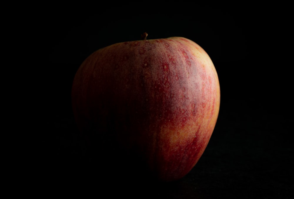 a red apple sitting on top of a black table
