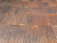 A close-up view of a corrugated metal roof with a rusted, aged appearance. The panels are aligned in a systematic pattern with alternating ridges and grooves. Various rust and weathering marks are present across the metal, adding texture and character.