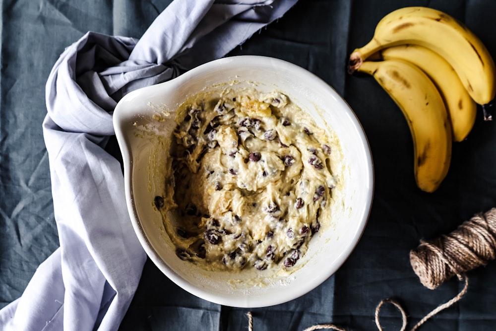 a bowl of oatmeal next to two bananas