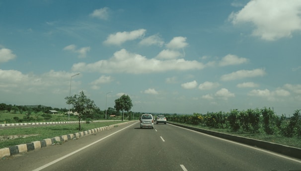 A scenic highway stretching ahead with a carpool vehicle cruising under a bright blue sky.
