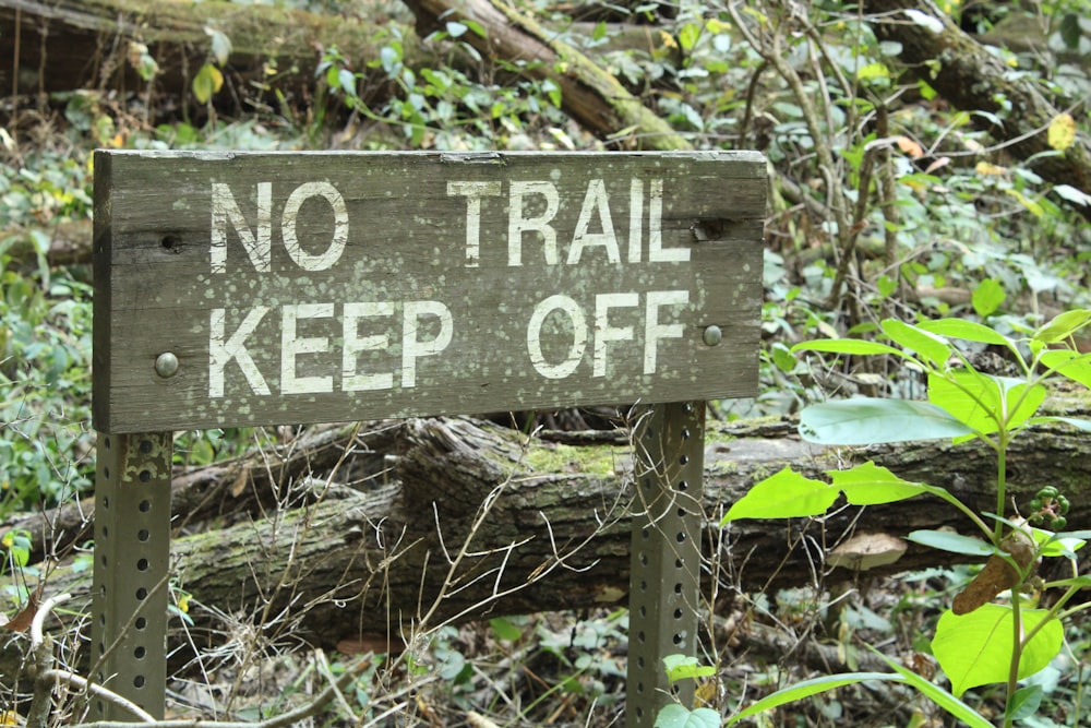 a wooden sign that says no trail keep off