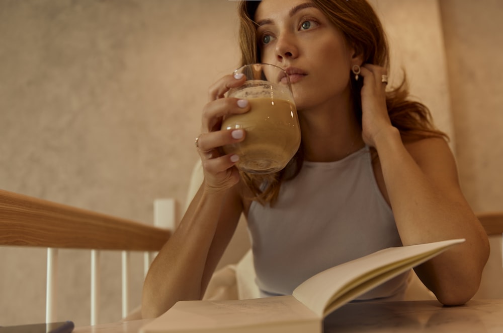 woman in white tank top drinking from clear drinking glass