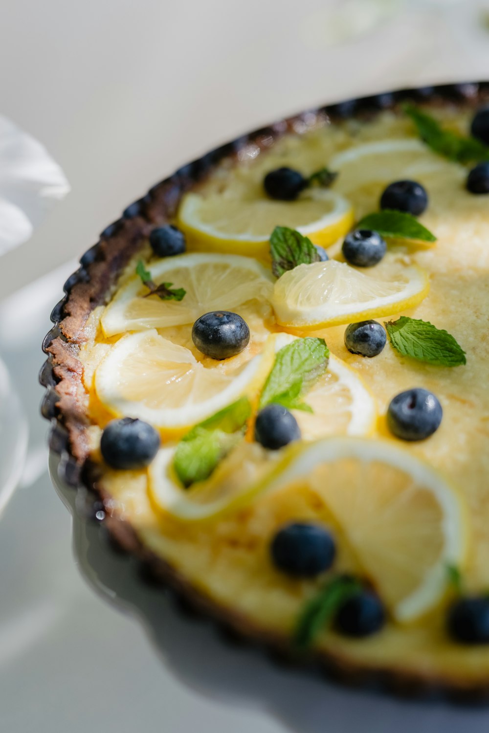 a pie with lemons, blueberries and mint on it