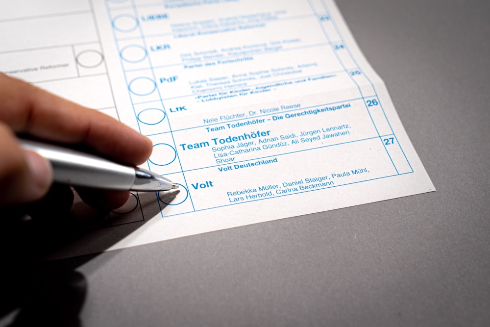 a person holding a pen over a piece of paper