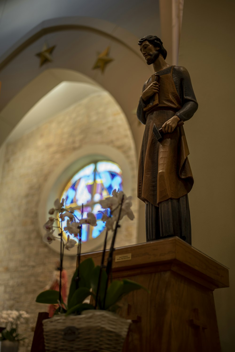 uma estátua de uma mulher em pé na frente de um vitral