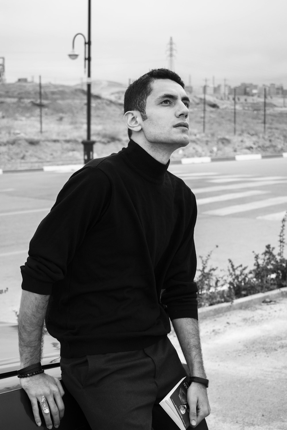 a man in a black turtle neck sweater leaning against a wall