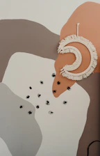 A softly lit close-up of a square artwork featuring abstract shapes and muted colors.