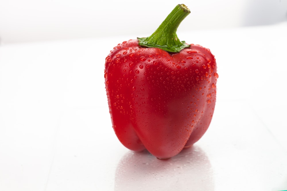 a close up of a red pepper on a white surface