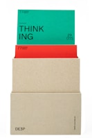 A beige box holds two cards. The top card is green with the word 'THINKING' prominently displayed in black text along with the phrase '(actional)' and other smaller text details. The card beneath is red, partially obscured by the green card, also containing textual information. The box has minimalistic text on its lower part.