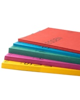 Stack of colorful folders and paper pads with a minimalistic background