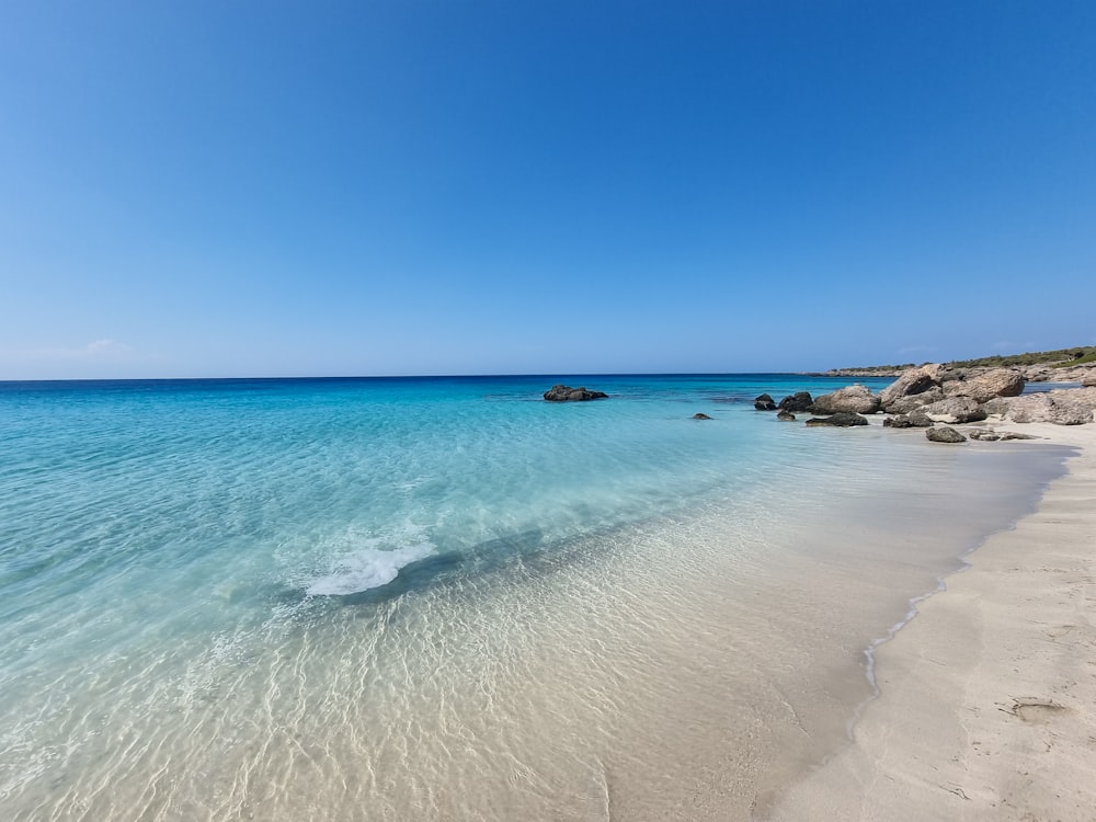 a beach with clear blue water and rocks