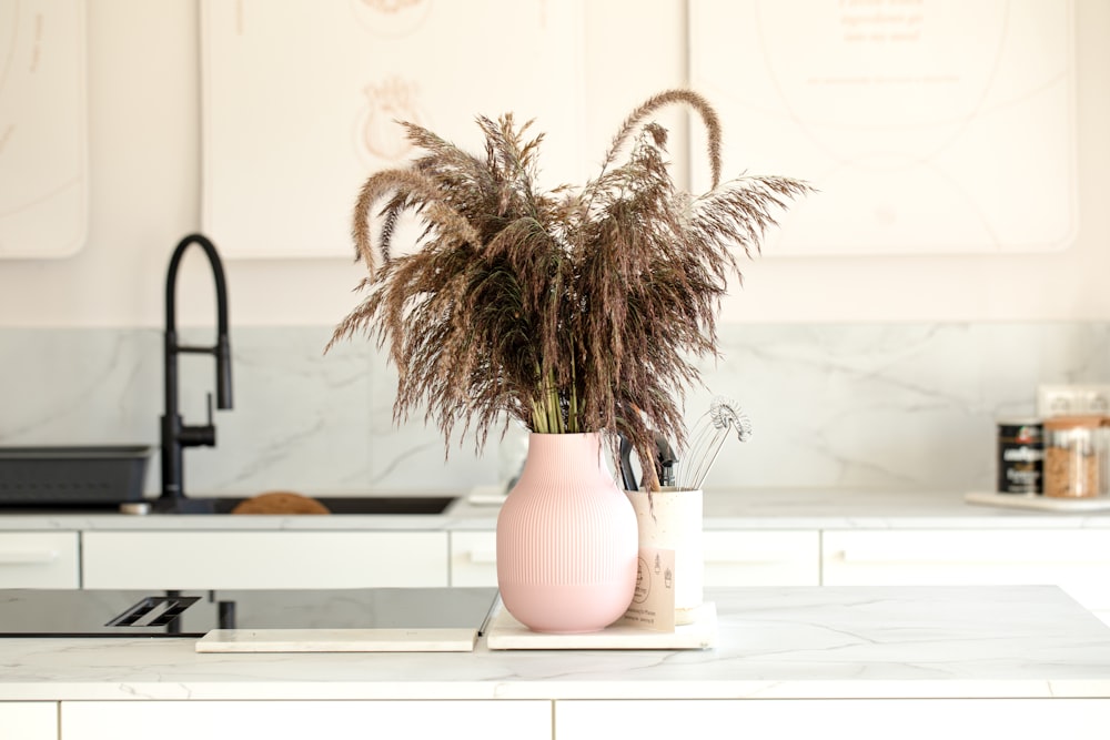 a pink vase with some plants in it