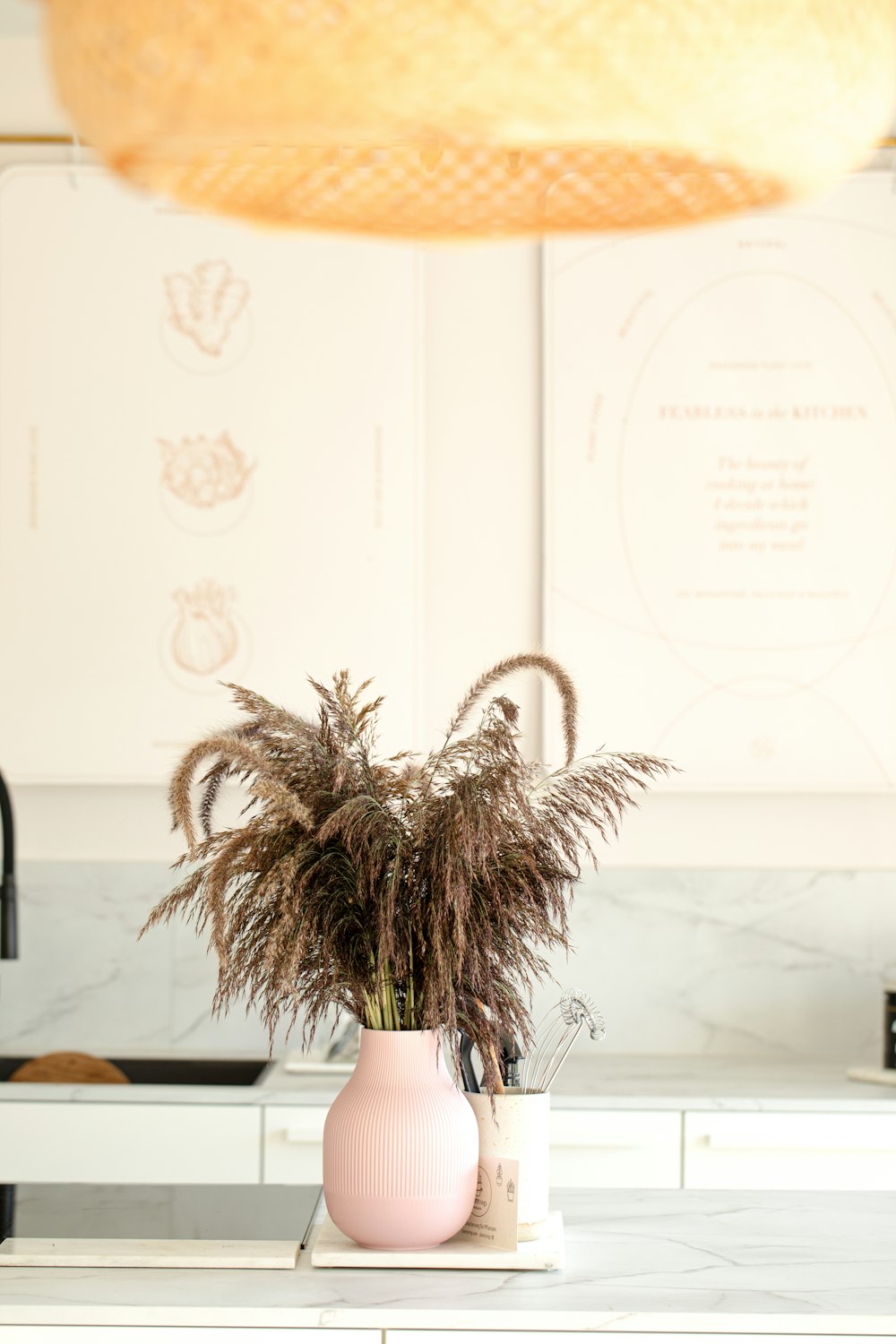 a pink vase with some plants in it