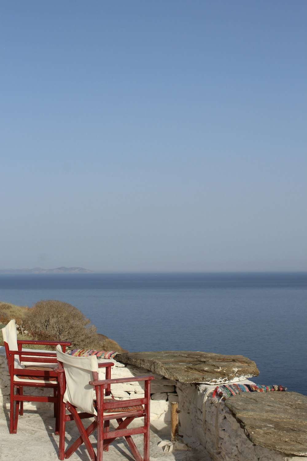 a couple of red chairs sitting on top of a stone wall