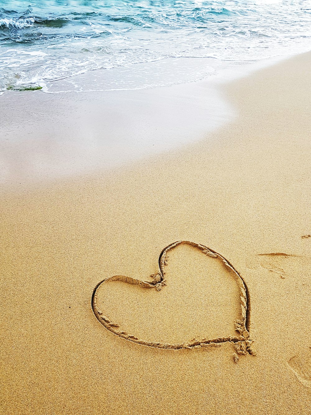 Un corazón dibujado en la arena de una playa