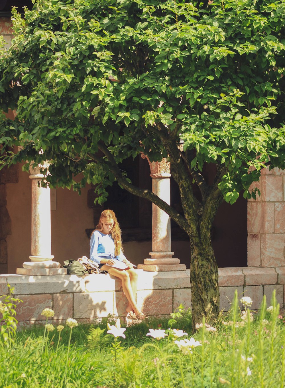 a woman sitting on a bench under a tree