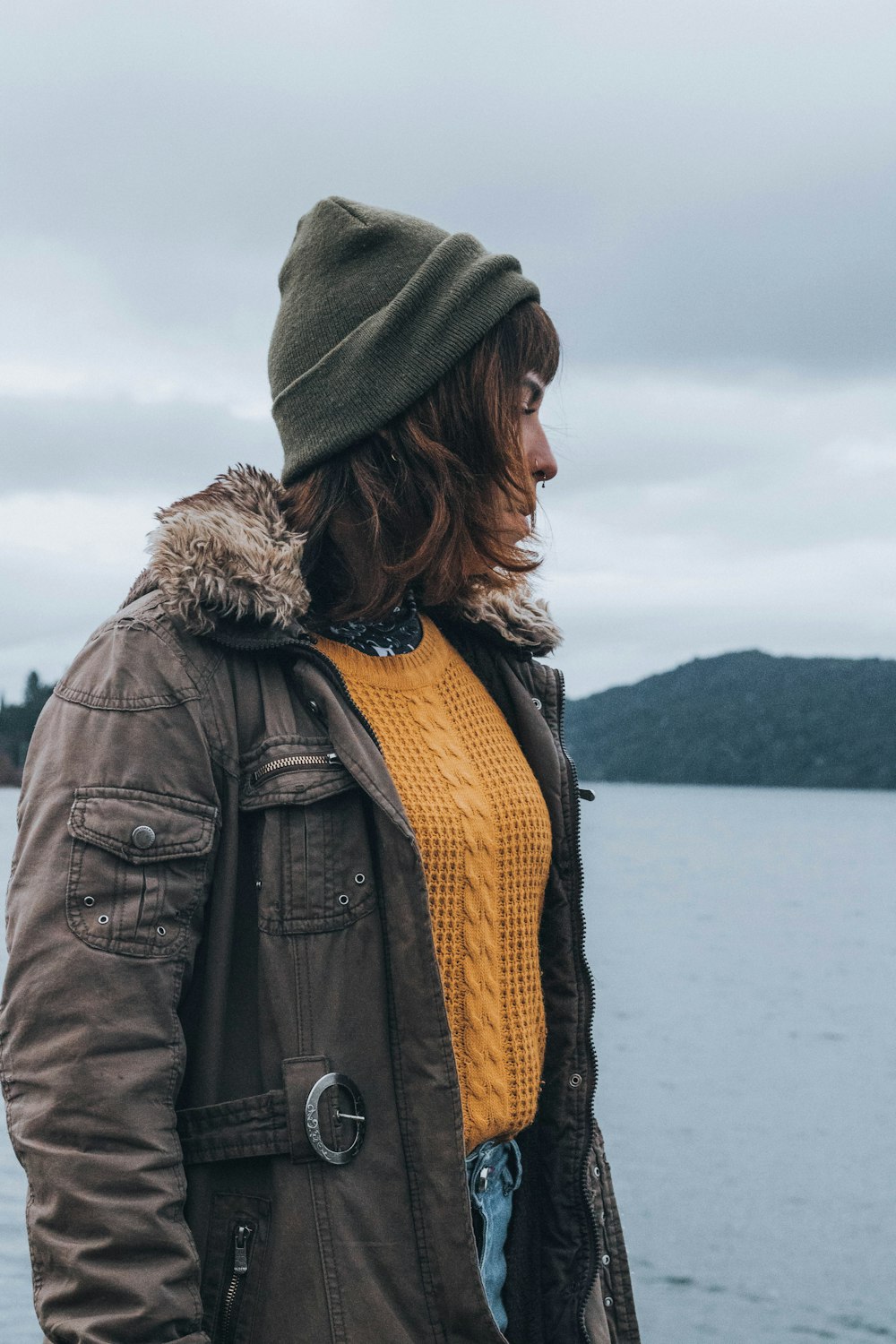 a woman wearing a brown jacket and a yellow sweater