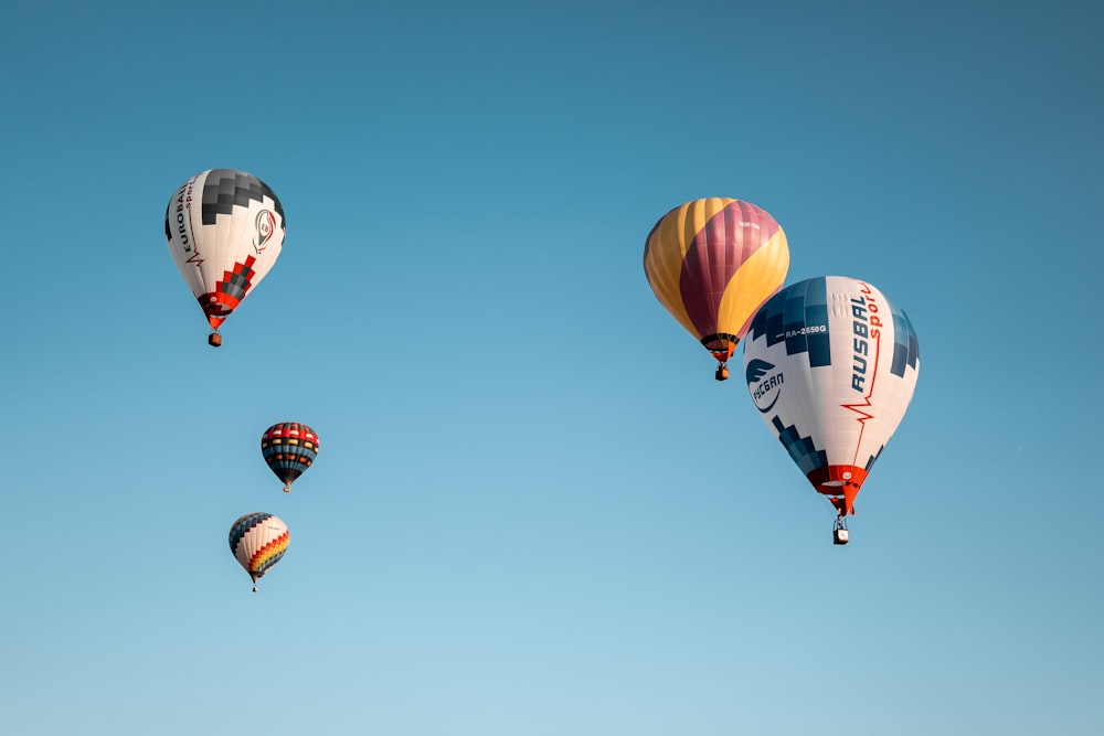 a group of hot air balloons flying through a blue sky