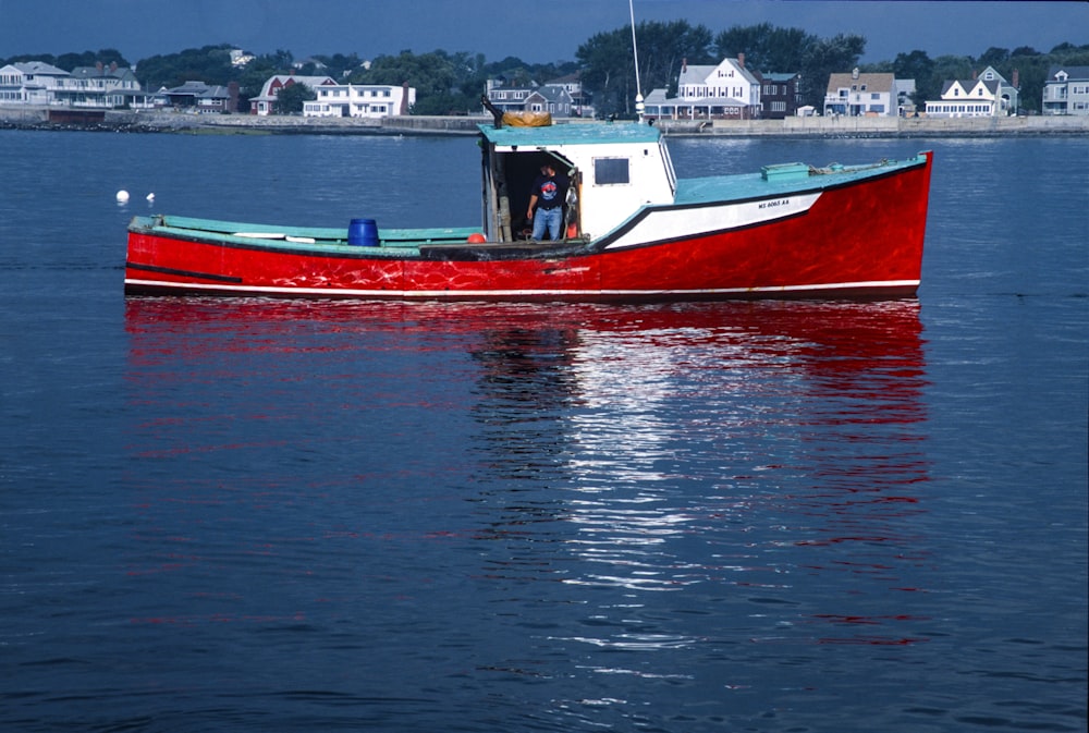 a red and white boat floating on top of a body of water