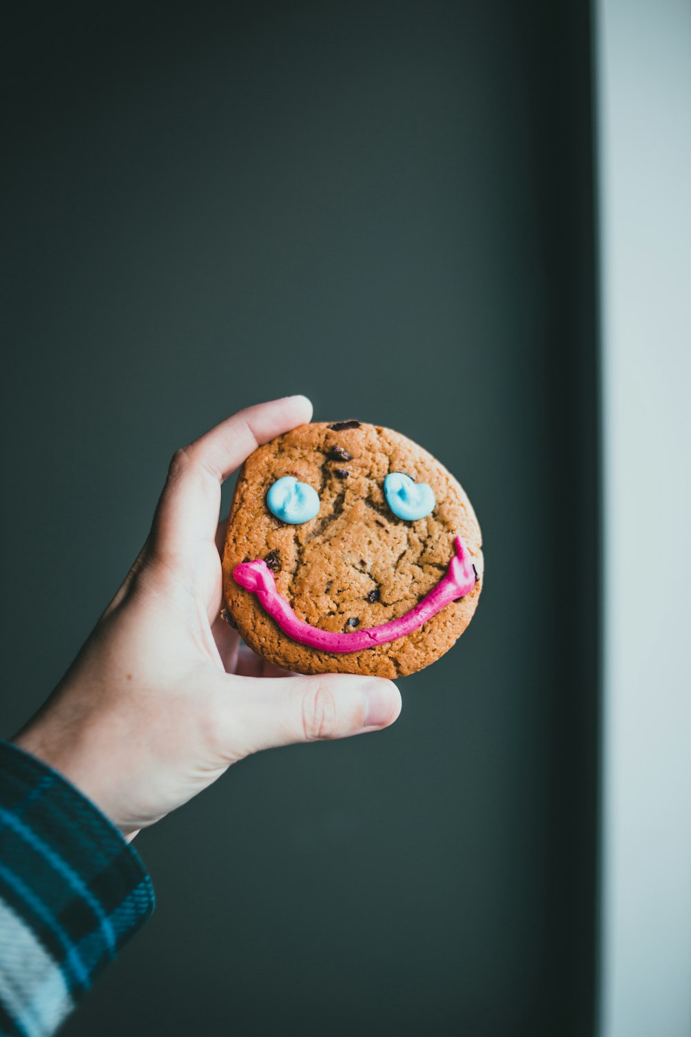 a person holding a cookie with a face painted on it