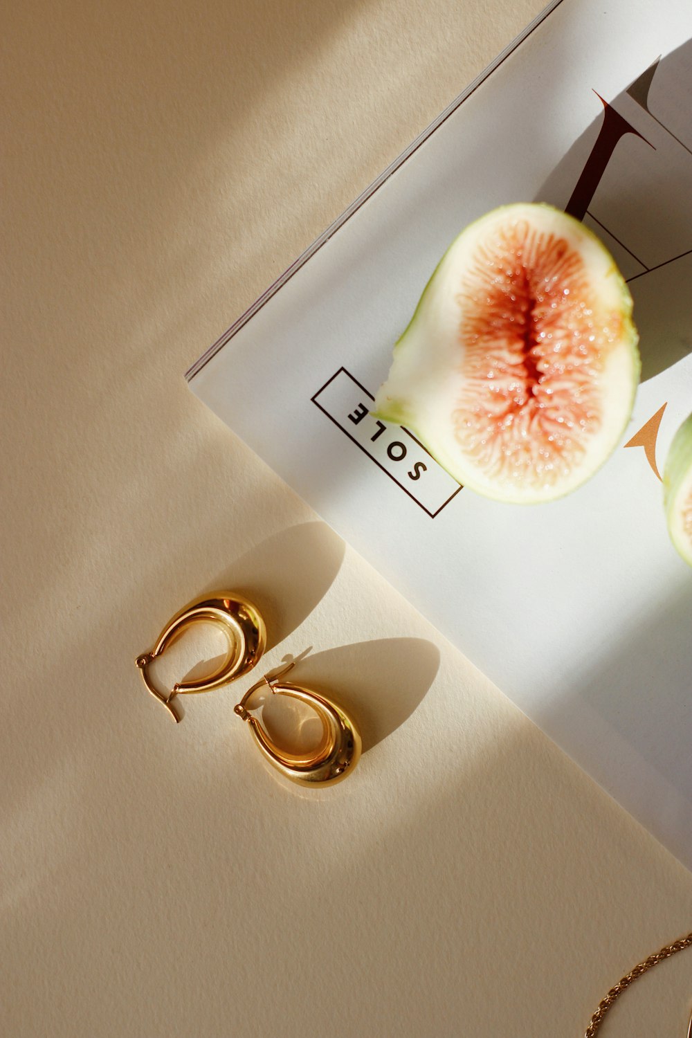 a piece of fruit sitting on top of a table next to a pair of gold