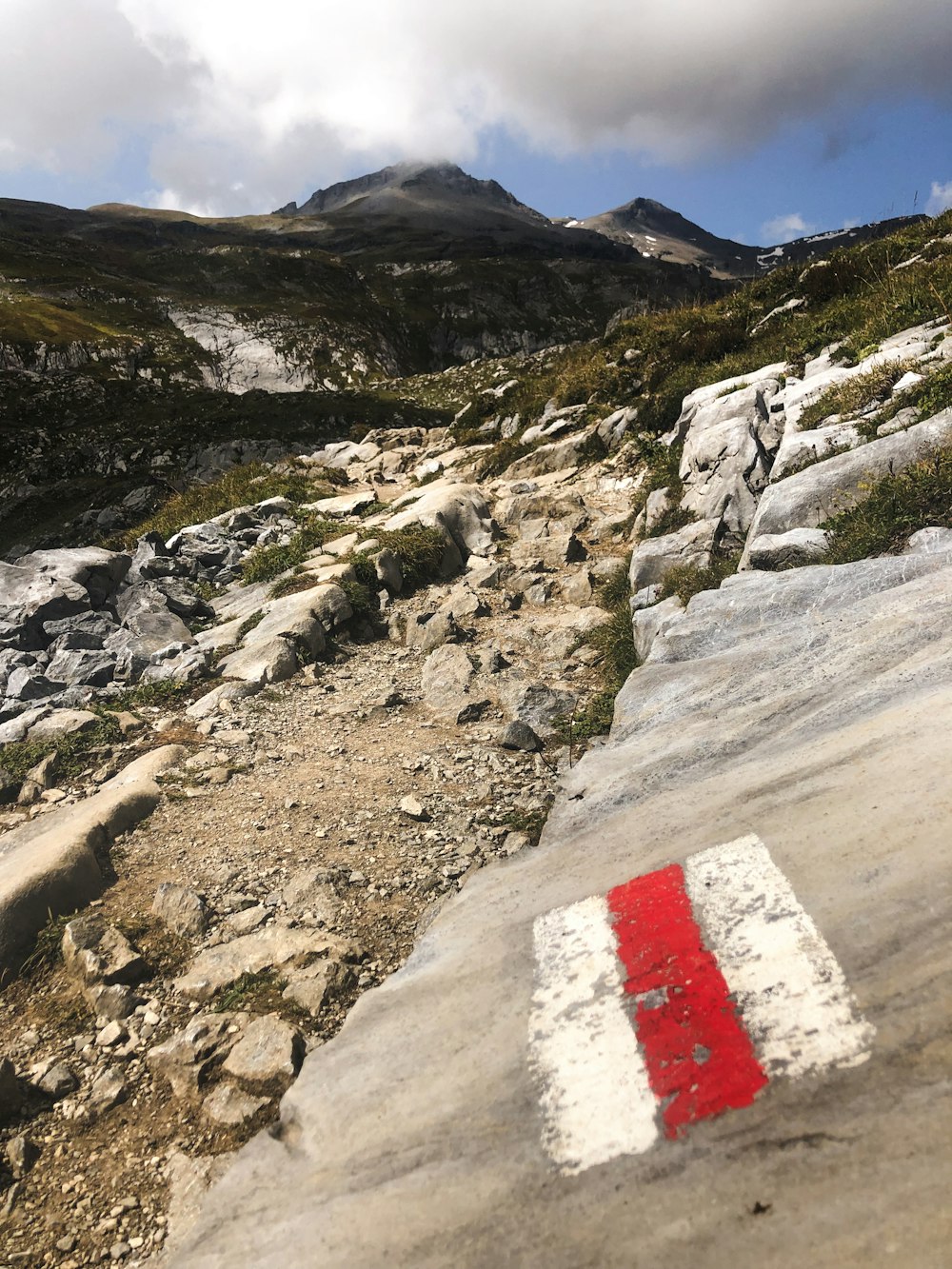 a red and white sign sitting on the side of a mountain