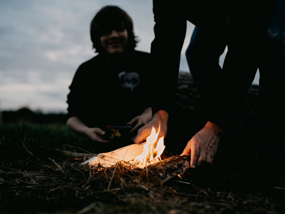 eine Person, die neben einem Feuer auf dem Boden sitzt