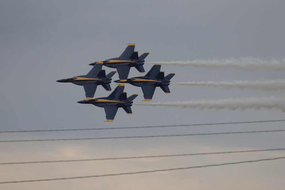 a group of fighter jets flying through a cloudy sky