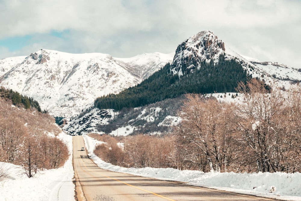 a snow covered road with mountains in the background