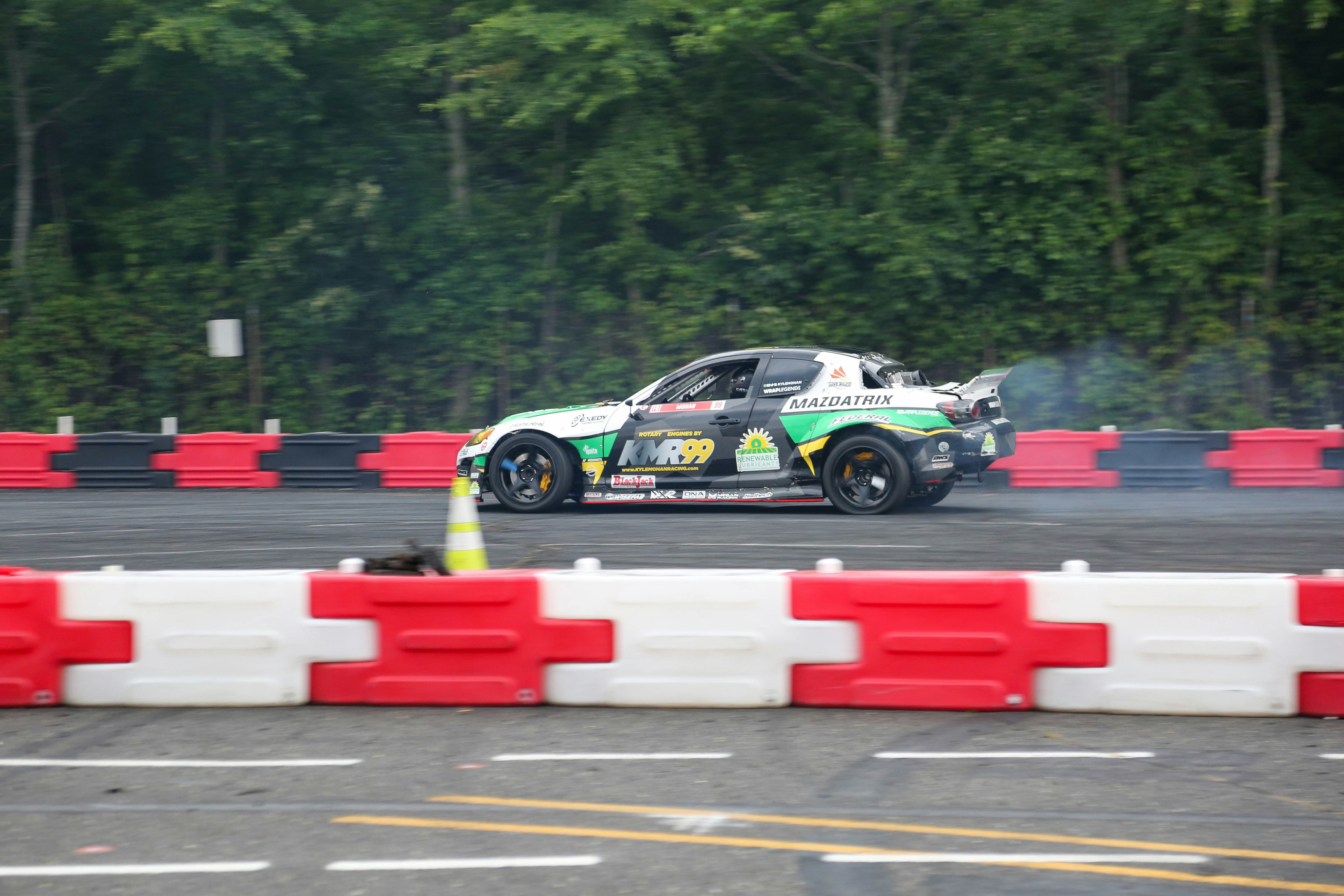 a car driving on a race track with trees in the background