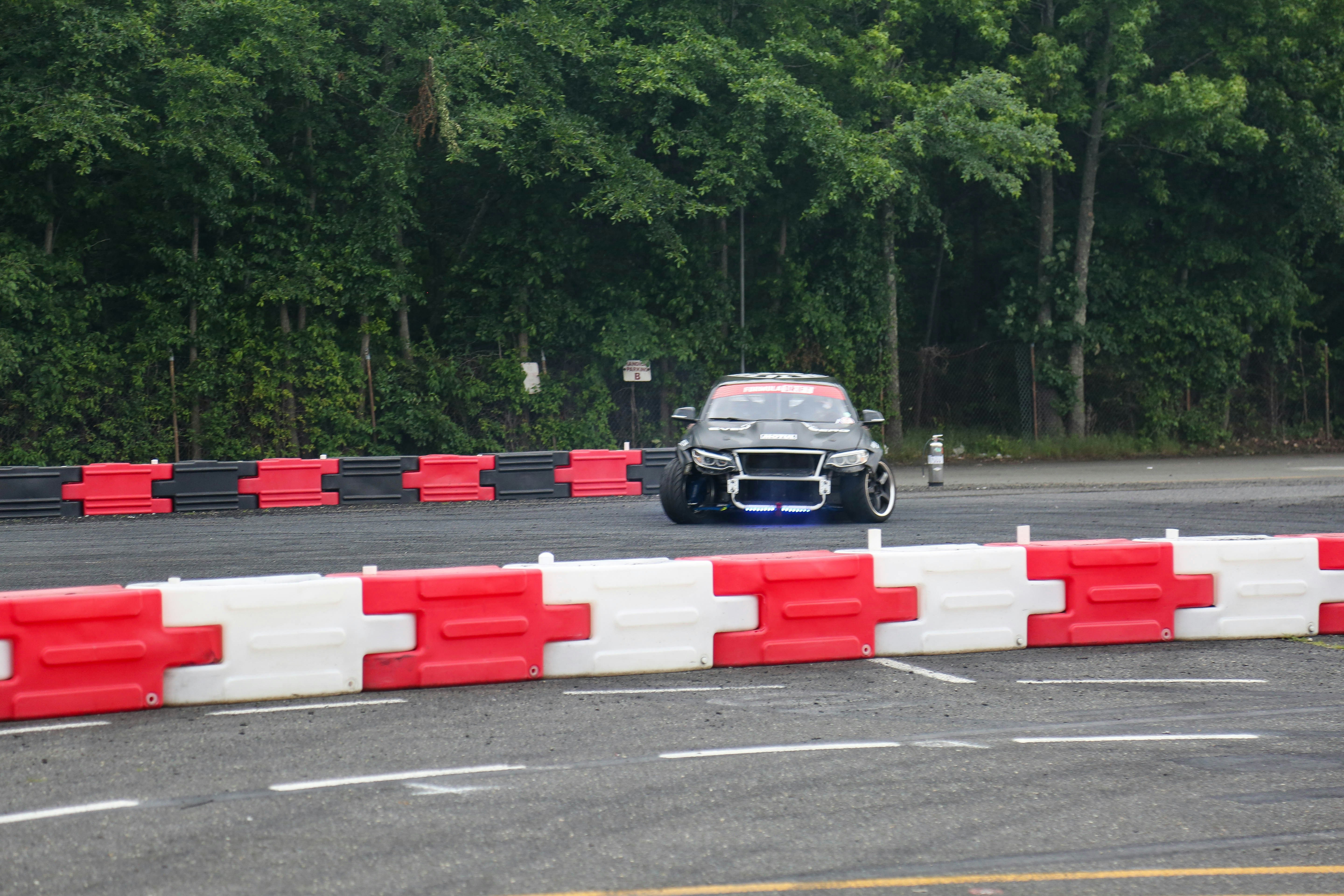 a car driving on a race track with a red and white barrier