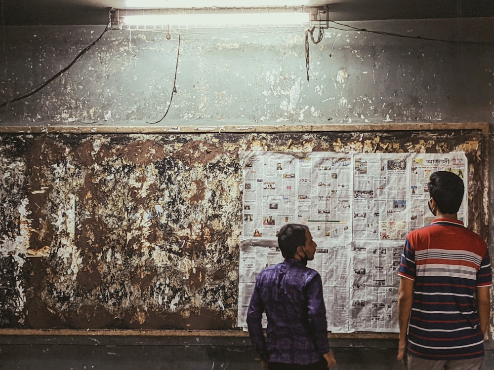 a couple of kids standing in front of a bulletin board