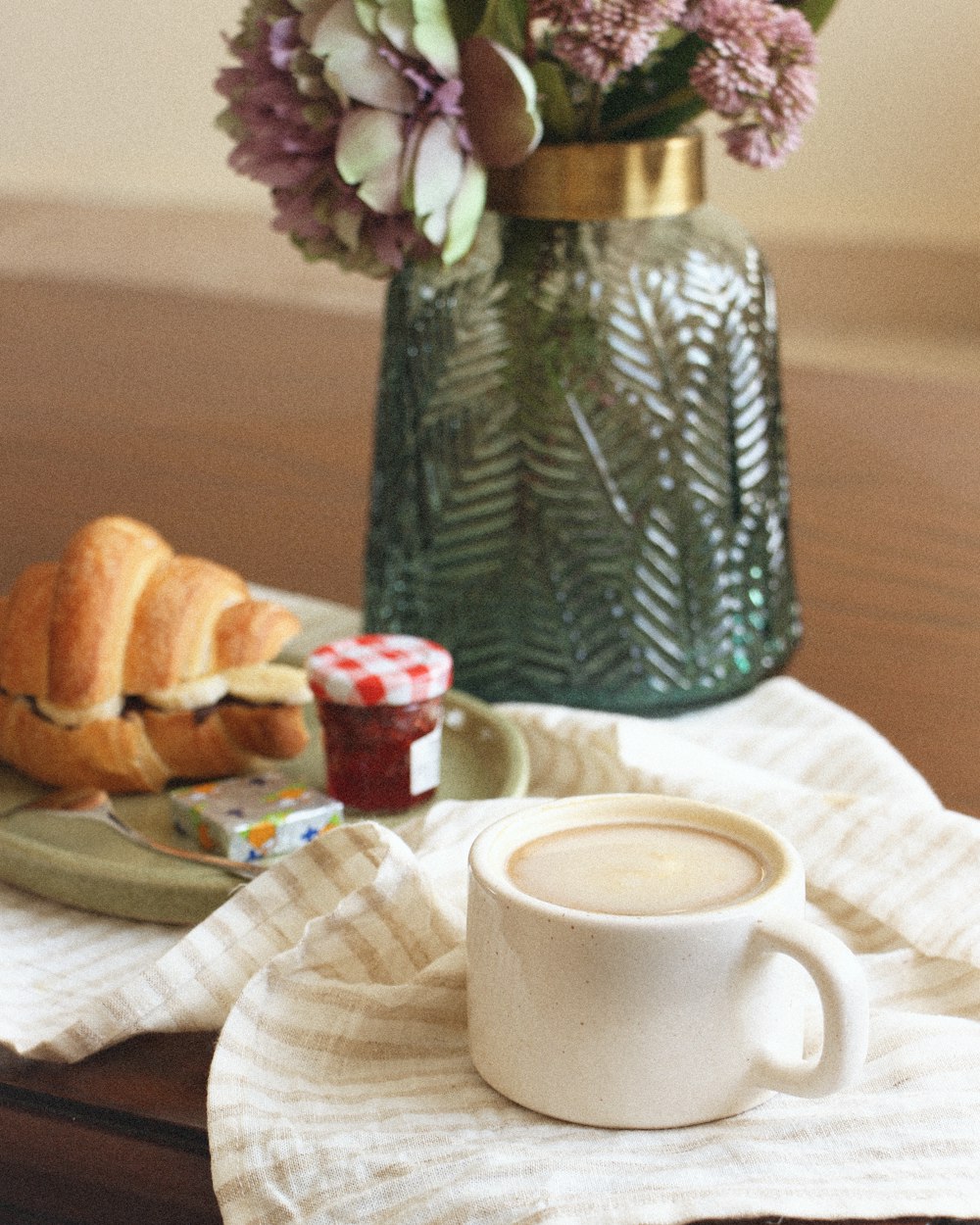 a cup of coffee sitting on top of a table next to a plate of food