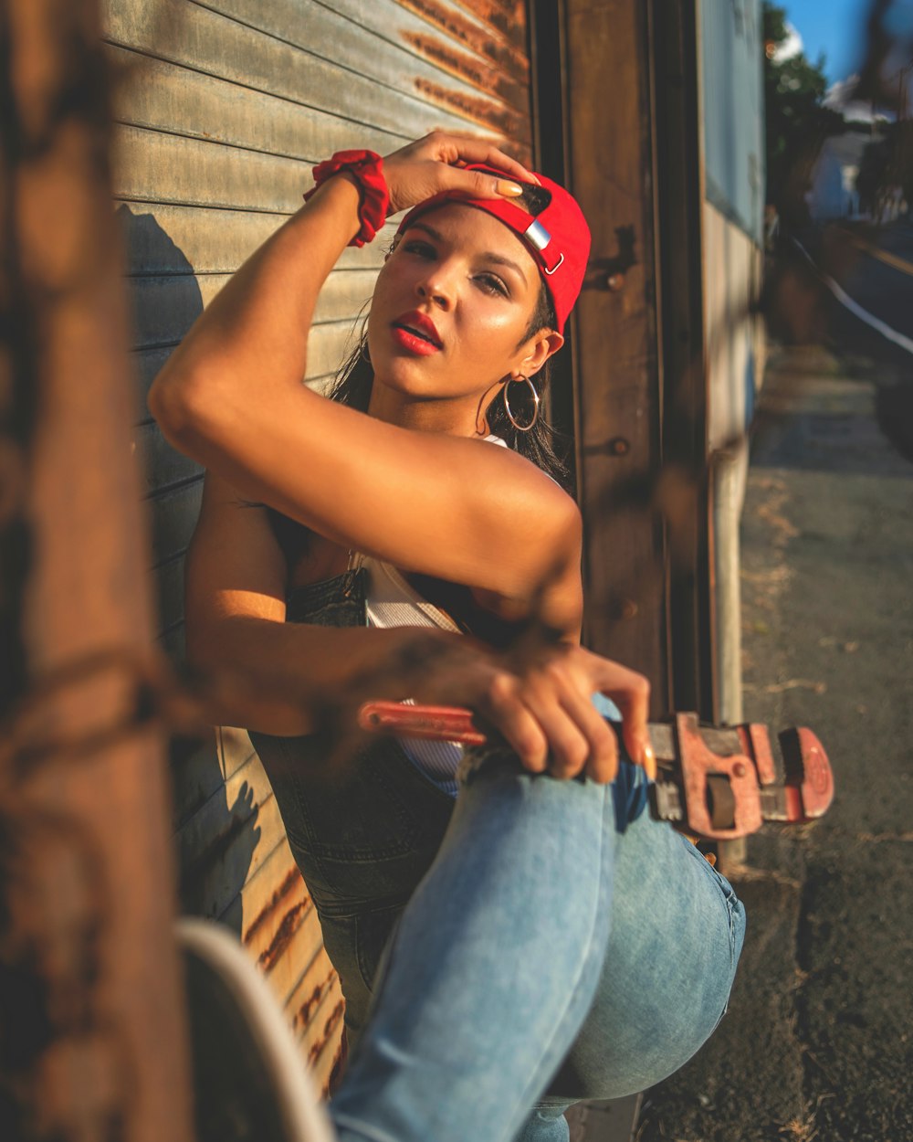 a woman leaning against a wall with a skateboard