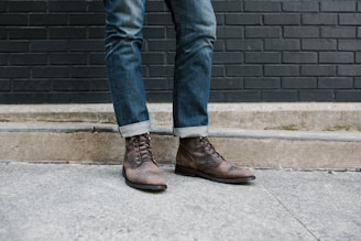 a person standing on a sidewalk wearing brown shoes
