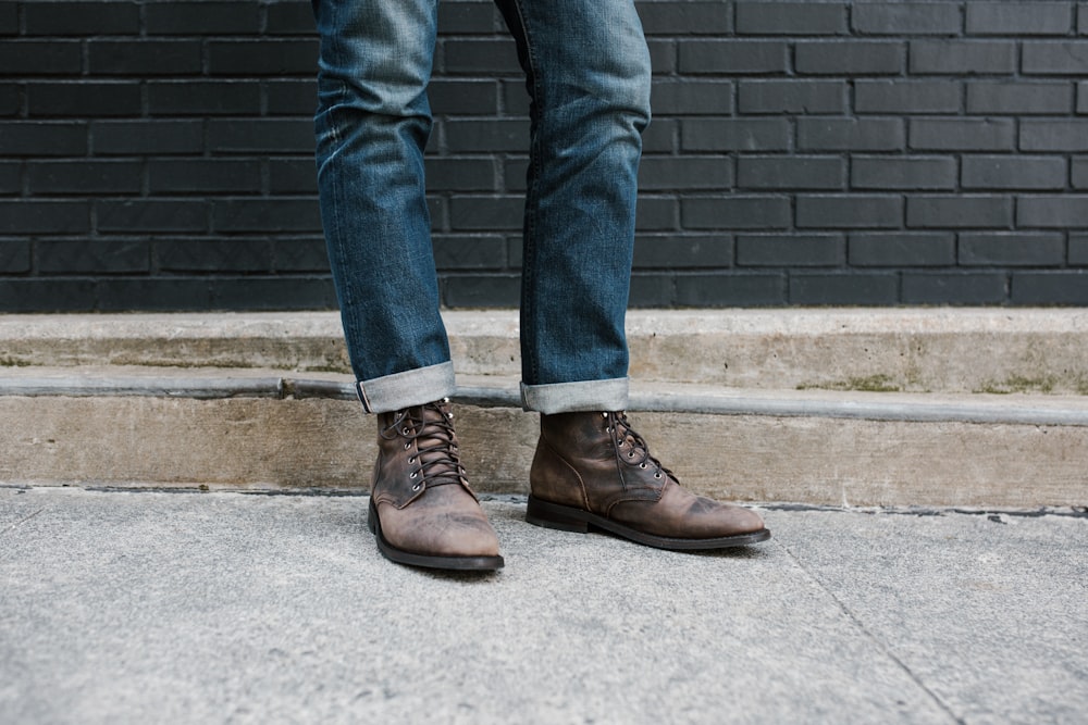 a person standing on a sidewalk wearing brown shoes