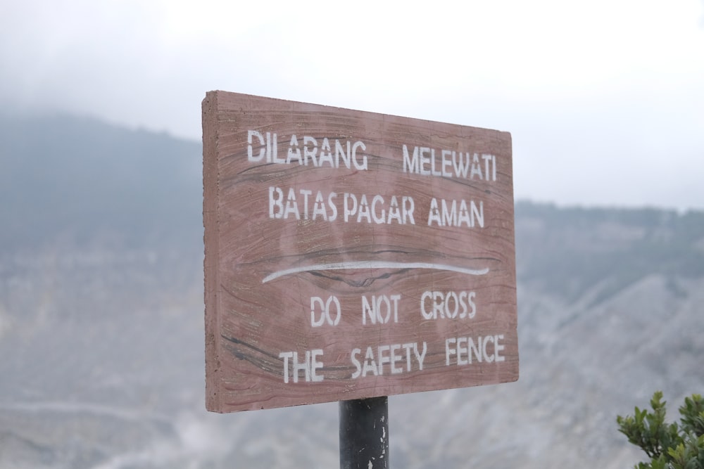 a sign on a pole with a mountain in the background