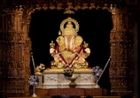 Intricately carved Hindu lord statue placed on a wooden pedestal.