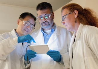 three people in lab coats looking at a tablet