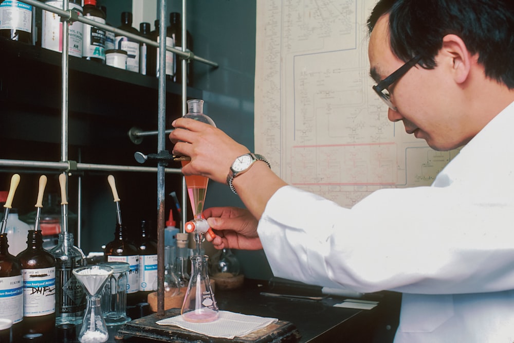 a man in a lab coat holding a beakle filled with liquid