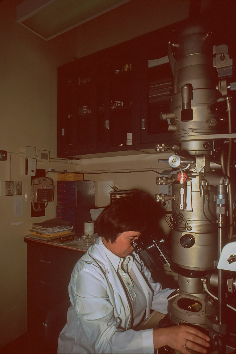 a woman looking through a microscope in a lab