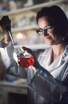 a woman in a lab coat is holding a flask of liquid