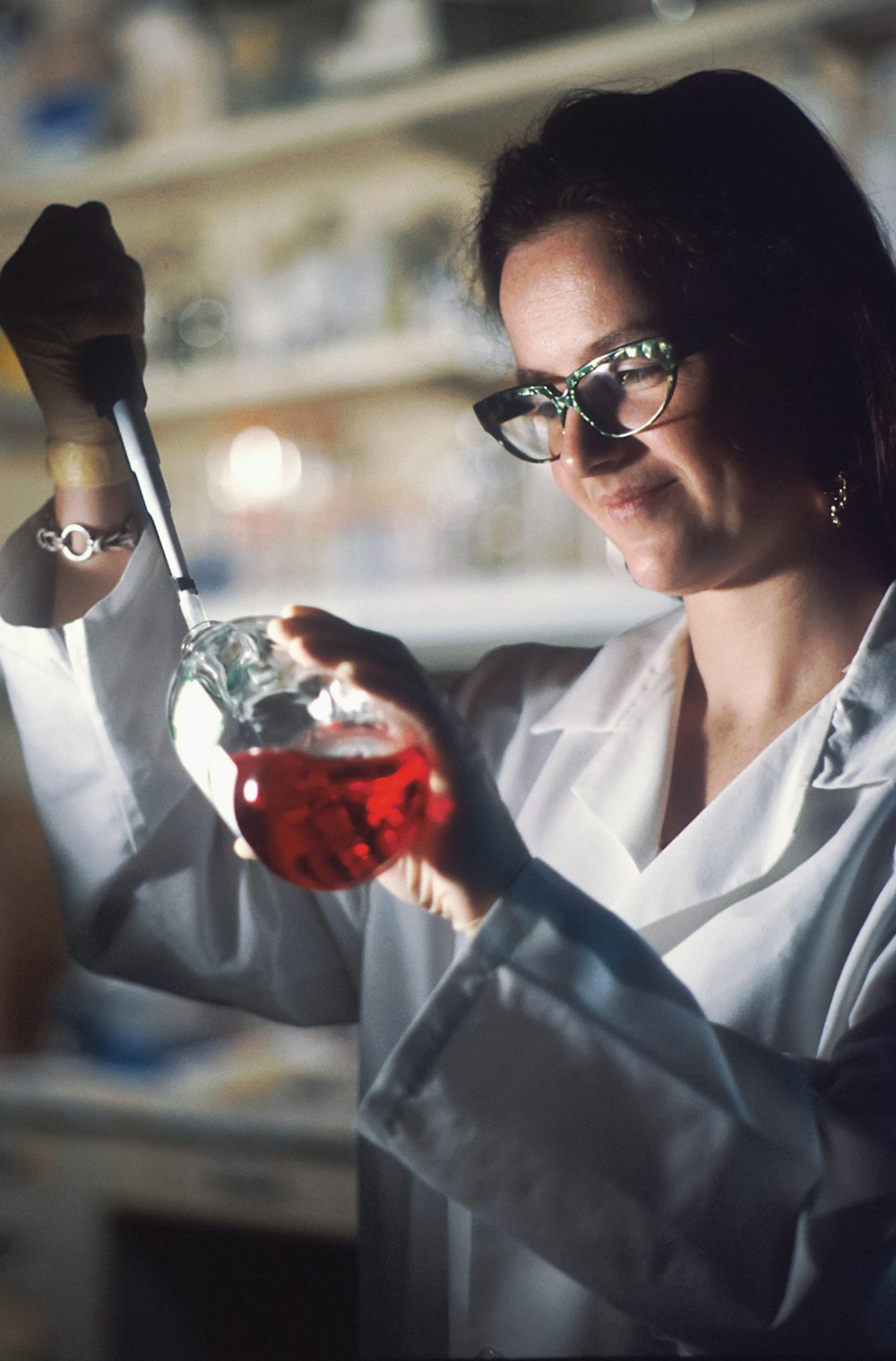 Eine Frau in einem Laborkittel hält eine Flasche Flüssigkeit in der Hand