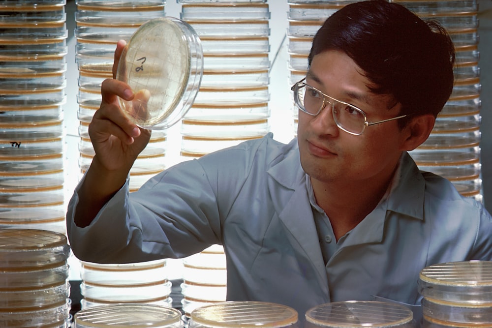 a man holding up a glass plate in front of stacks of plates