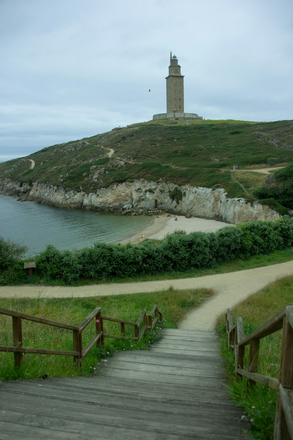 a wooden path leading to a lighthouse on a hill