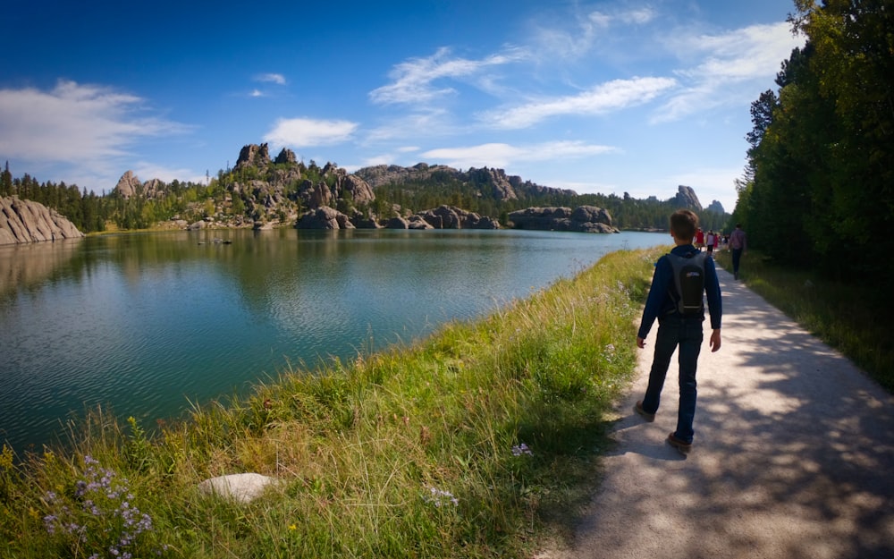 a man walking down a path next to a lake