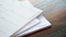 a stack of papers sitting on top of a wooden table